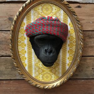 Tête de singe coiffée d’un bonnet rouge et encadrée